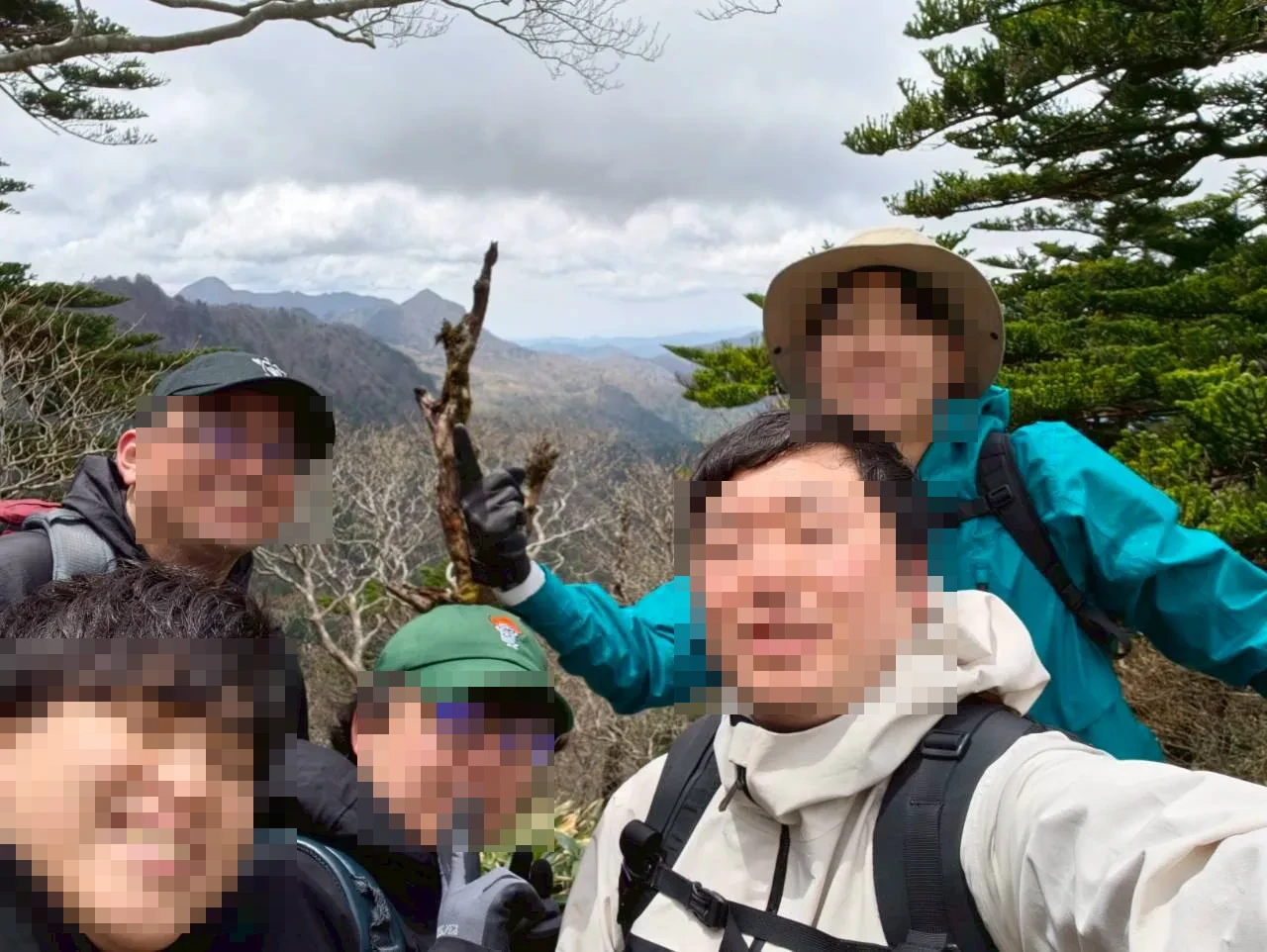 石鎚山の稜線上での集合写真。背後に山並みが広がる晴れた空が見える。